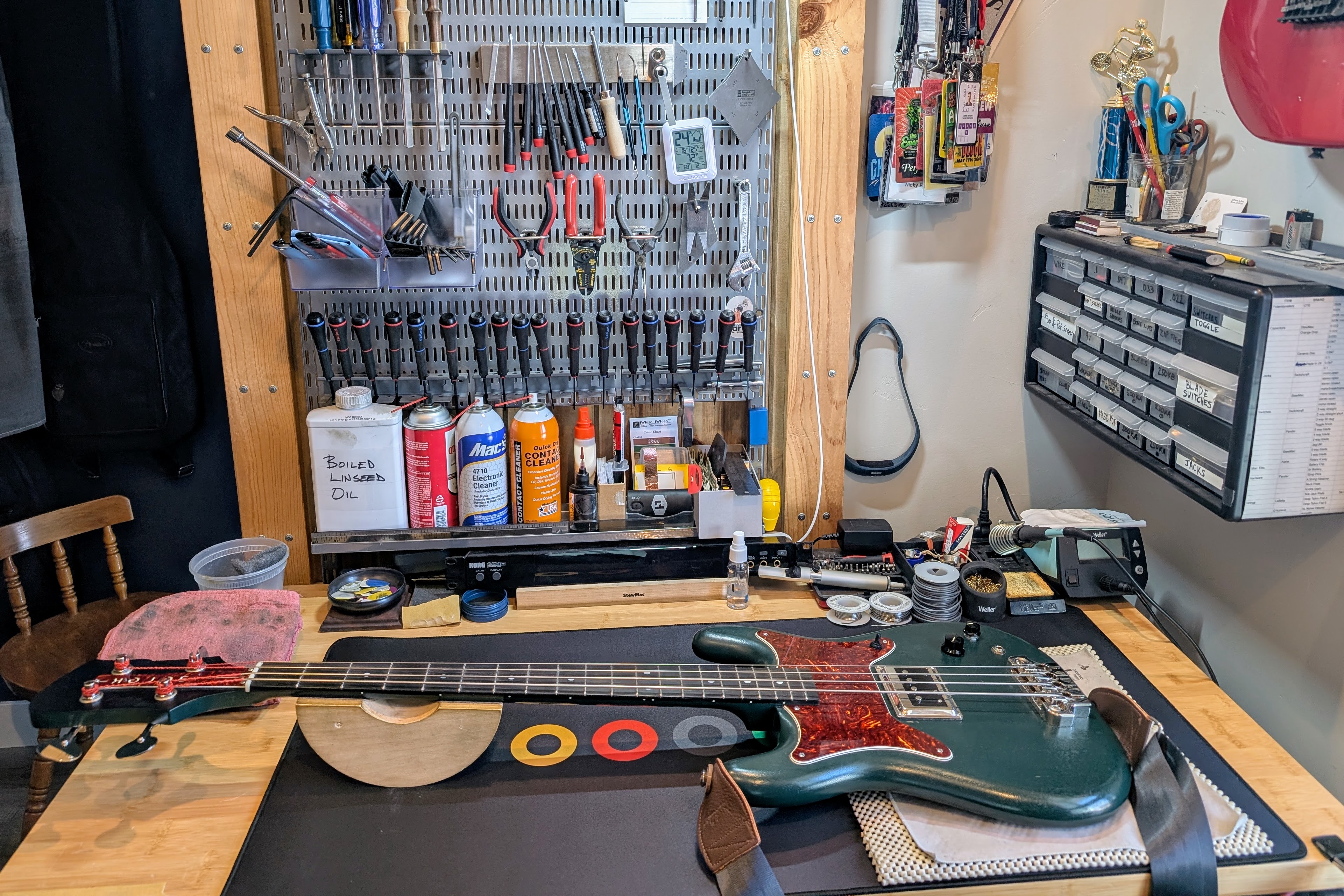 Electric bass on Dan's repair bench with setup tools and parts organized behind it